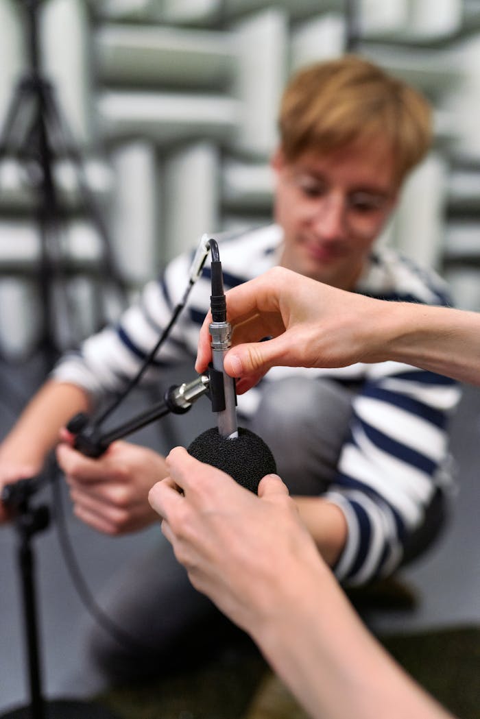 A sound engineer carefully adjusts a microphone in an acoustically treated recording studio.